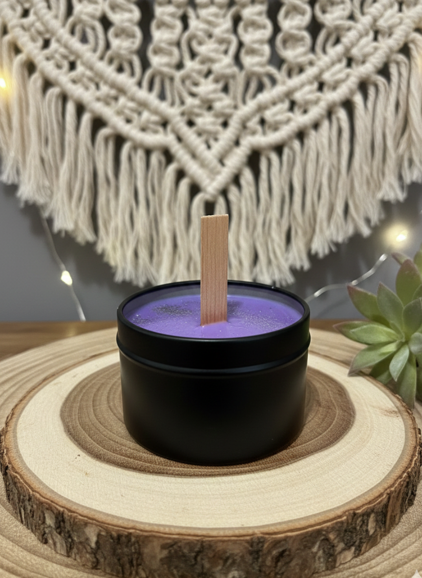 Black container with a purple candle on a wooden surface with macrame and succulent in the background